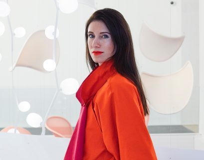 Brokis art director Lucie Koldova in a red coat in front of some of her lighting designs.
