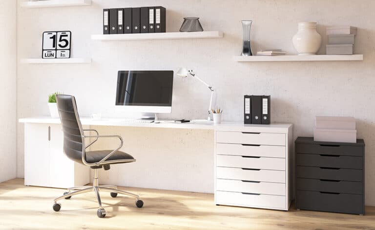 Modern white home office desk setup with a computer monitor, desk lamp, and organized shelves above.