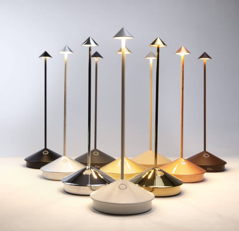 Row of tall modern table lamps with cone-shaped shades in black, silver, and gold on a white surface.